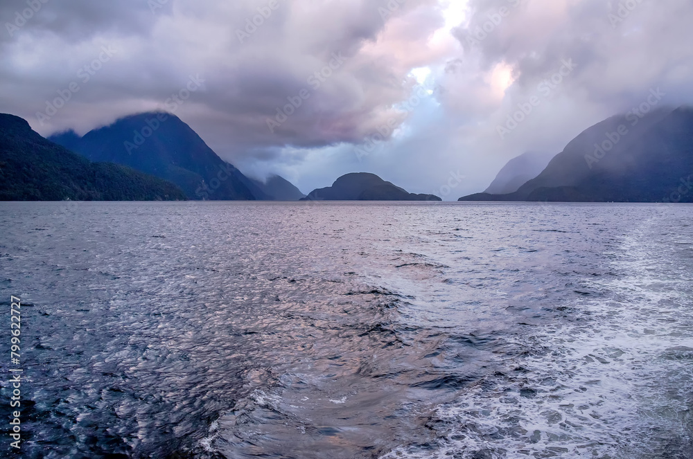 Seascape, dawn and early morning over the water in a fjord in cloudy weather, Doubtful Sound Fiord, New Zealand
