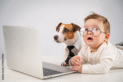 Cute baby boy and Jack Russell terrier dog working on a laptop. 