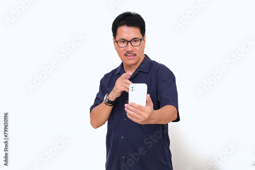 A middle-aged man holding a smartphone and pointing at it photo