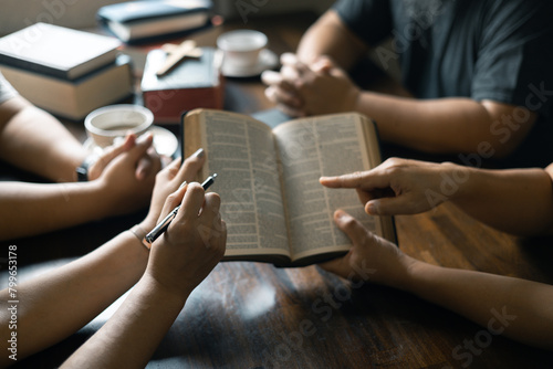 Christian woman held her Bible close as she joined hands with the group in prayer, their faith uniting them together in a religious bond during their prayer session. Group christian pray concept. © doidam10