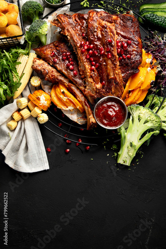 Pork ribs with vegetables on black background. Food for picnic concept © bit24