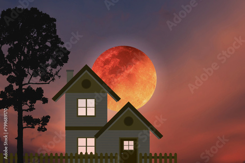 Small country house with silhouette big tree and big blood moon on dramatic colorful twilight sky.