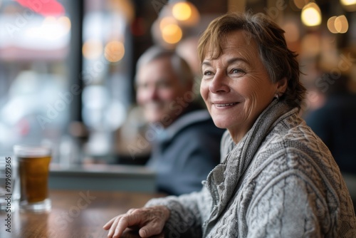 Portrait of happy senior woman sitting at table in pub, looking at camera.