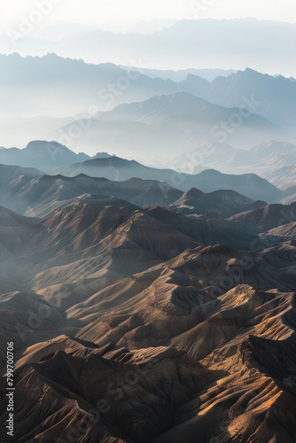 Aerial view of layered patterns of mountain ridges receding into the distance  with their alternating light and shadow creating a minimalist composition.