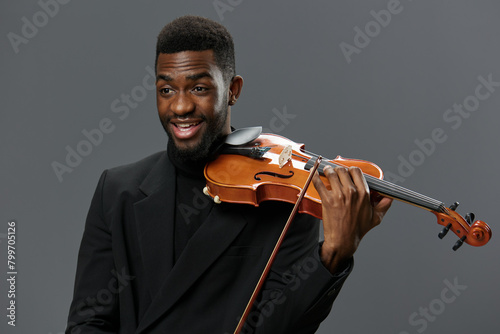 Professional African American musician in elegant suit holding a violin on a neutral gray background photo