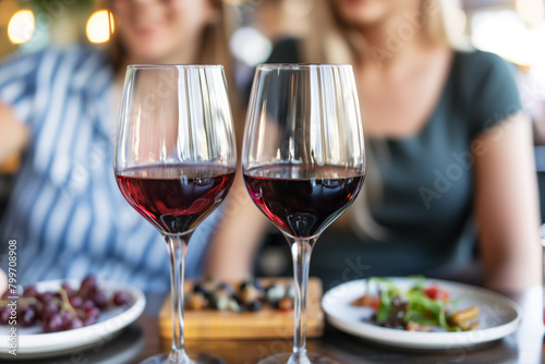 Two glasses of red wine on the table  with people in the background blurred out