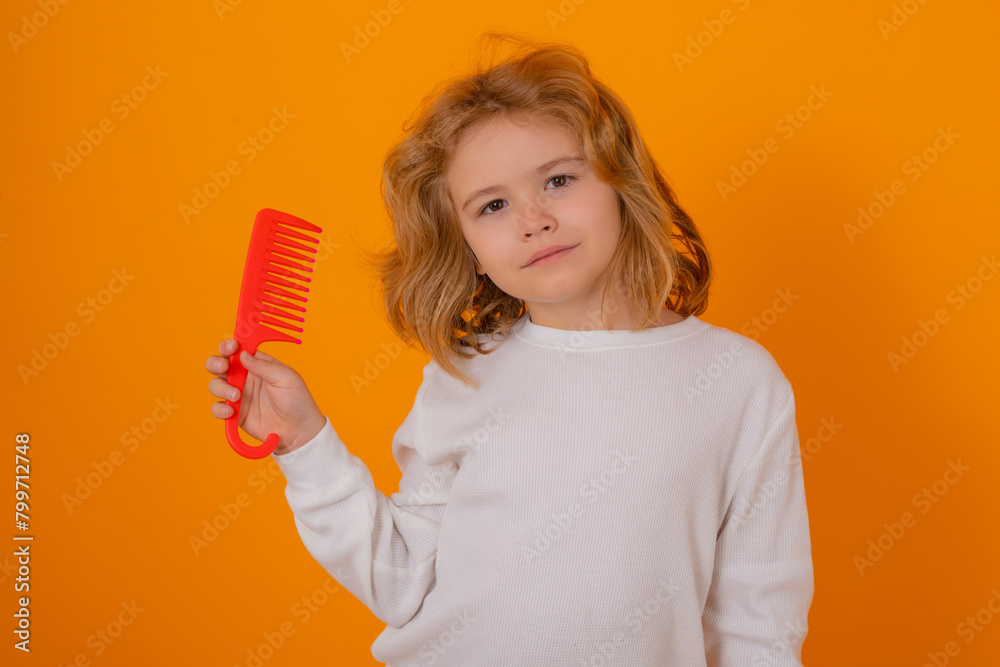 Portrait of child combing hair with comb on yellow studio background. Kid boy makes funny face expressions, combing hair. Child with brush combing hair. Boy taking hairstyle. Portrait of child combing hair with comb on yellow studio background. Kid boy makes funny face expressions, combing hair. Child with brush combing hair. Boy taking hairstyle.