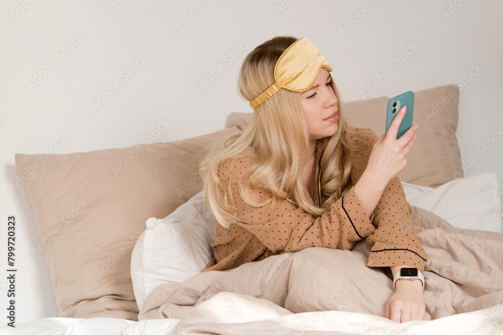 Woman in bed checking phone, concerned look. Woman in bed checking phone, concerned look.