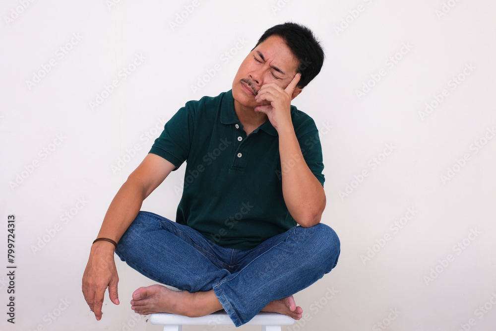 A man sitting on a stool is closing his eyes, while hand supporting his head A man sitting on a stool is closing his eyes, while hand supporting his head