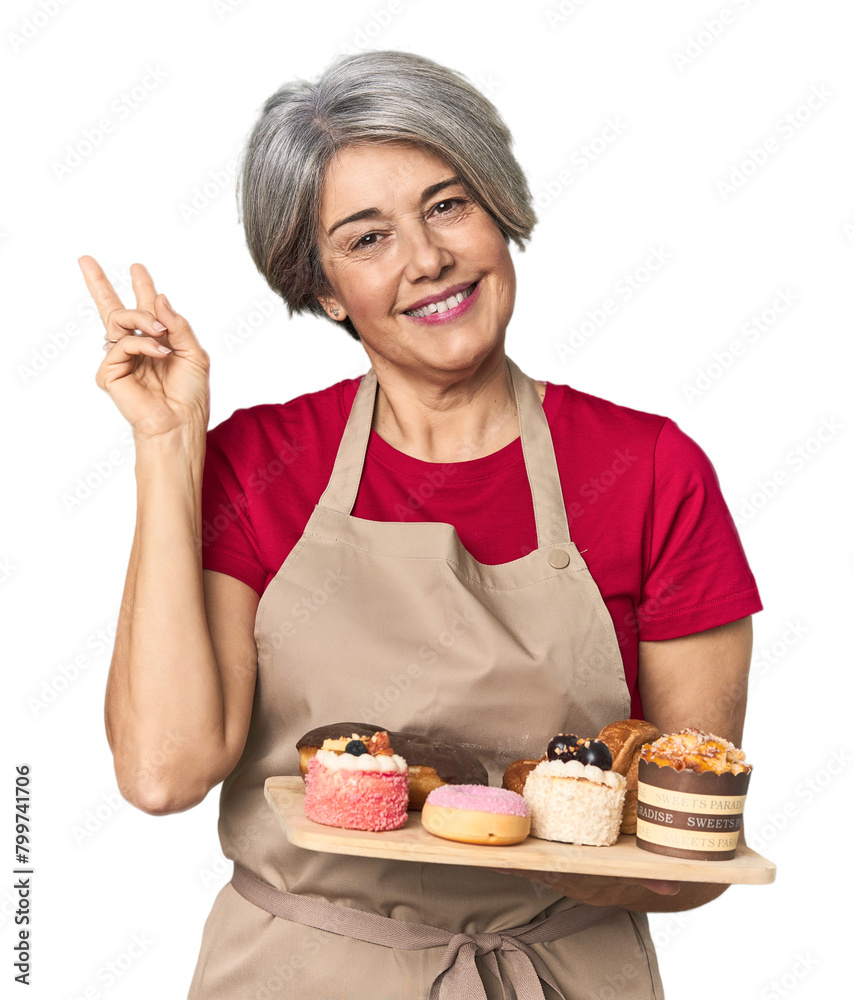 Caucasian mid-age baker with pastry tray joyful and carefree showing a peace symbol with fingers. Caucasian mid-age baker with pastry tray joyful and carefree showing a peace symbol with fingers.