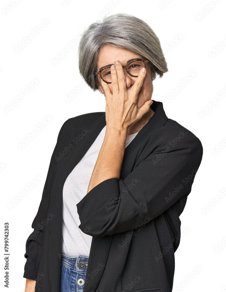 Caucasian mid-age female in business suit blink at the camera through fingers, embarrassed covering face. Caucasian mid-age female in business suit blink at the camera through fingers, embarrassed covering face.