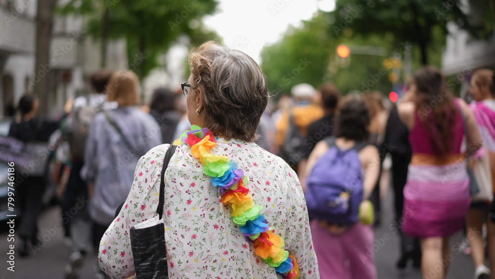 Old lady support lgbt gay community. Aged grandma wear rainbow hawaii lei flowers. Free bi sexual granny enjoy rest csd day. Happy lesbian women walk city street. Joyful grand mum have fun pride fest.