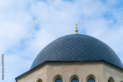 Close-up shot of the gambiz dome with a crescent moon on top of a Muslim mosque against a blue sky photo