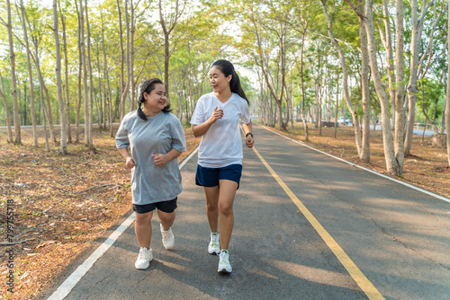 Two happy Asian female friends running together in the morning at a running park on a summer day © kudosstudio