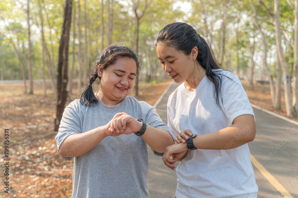 Two young female friends checking out their run time on their smart watch after their morning run at a local running park Two young female friends checking out their run time on their smart watch after their morning run at a local running park