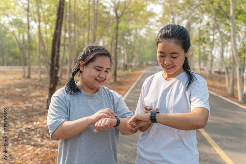 Two young female friends checking out their run time on their smart watch after their morning run at a local running park