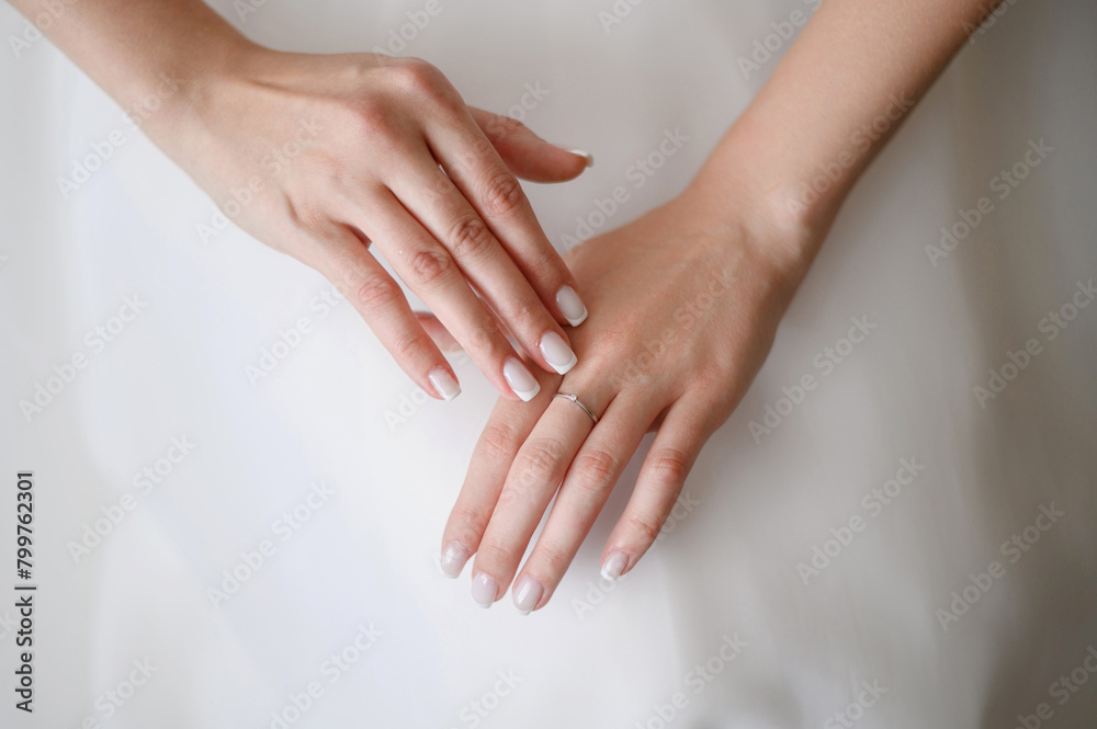 Beautiful gentle hands of bride with neat manicure in white wedding dress with wedding ring on her hand. Bride touches ring with her fingers. Wedding day, bride morning concept. Beautiful gentle hands of bride with neat manicure in white wedding dress with wedding ring on her hand. Bride touches ring with her fingers. Wedding day, bride morning concept.