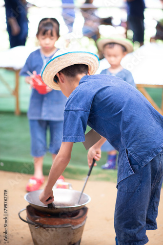 Smiling kids cooks together outdoors with a fried egg