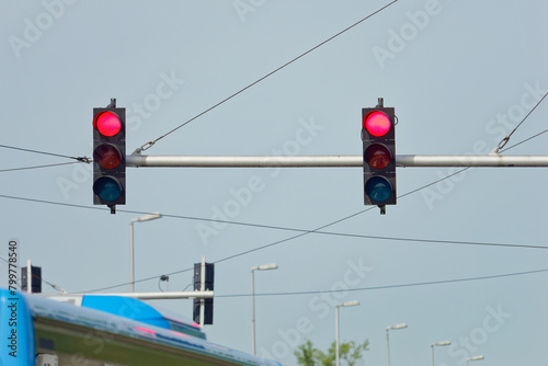 Red traffic lights on a metal pole with a clear blue sky in the background photo