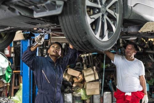 Black woman car mechanic working with Asian technician fixing car in auto repair shop