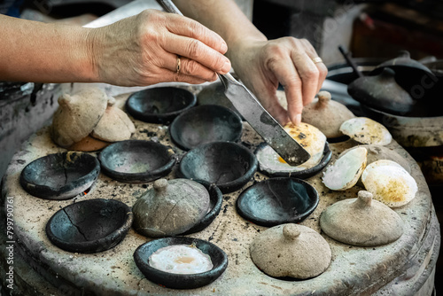 Fototapeta Naklejka Na Ścianę i Meble -  Vietnamese mini fried eggs, with rice flour, street cooking. Woman preparing Traditional Vietnamese breakfast Banh can