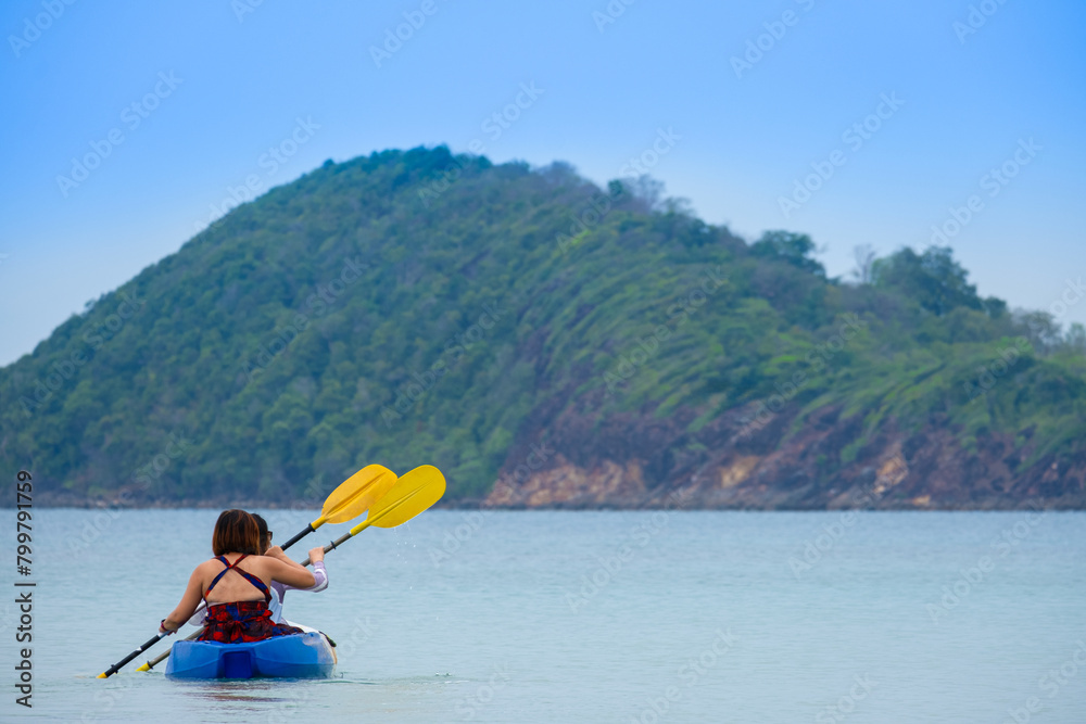 Aerial view of a woman and a young man kayaking on clear blue waters at Andaman Island. She does water sports activities.	