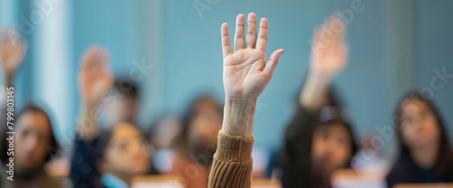 The hand of one person was raised in the audience while listening to an interview at a business conference or presentation. During the training class  people were sitting and raising their hands to as