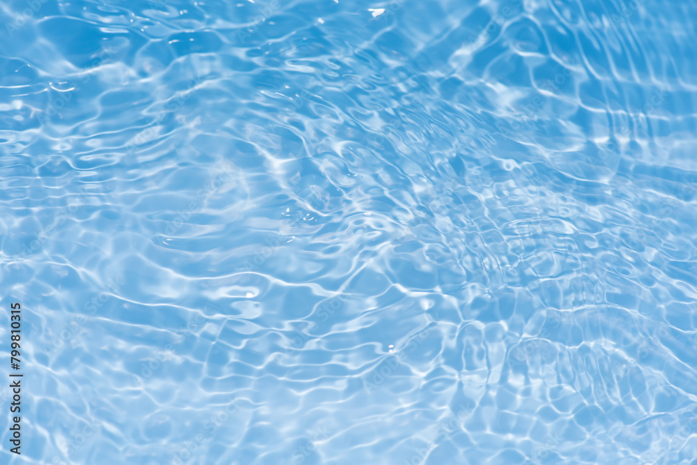 Obraz premium Bluewater waves on the surface ripples blurred. Defocus blurred transparent blue colored clear calm water surface texture with splash and bubbles. Water waves with shining pattern texture background.