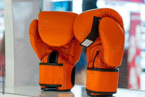 Boxing orange gloves on the shelf of the fightwear shop. Boxing gloves display at sports store. Fight shop, boxing equipment