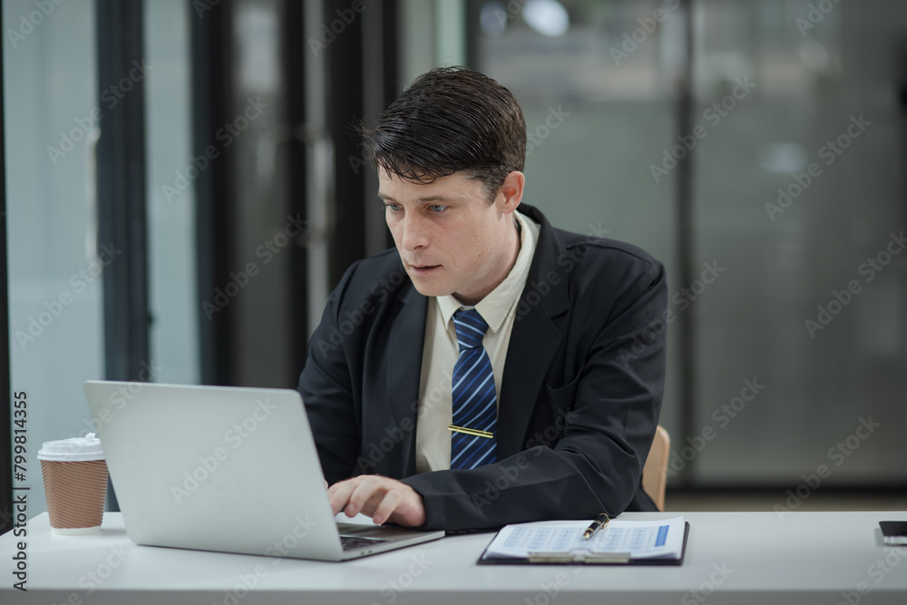 Professional business man trader using laptop computer sitting at office desk in modern office. Professional business man trader using laptop computer sitting at office desk in modern office.