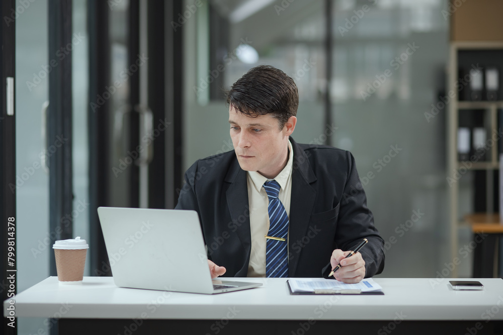 Professional business man trader using laptop computer sitting at office desk in modern office. Professional business man trader using laptop computer sitting at office desk in modern office.