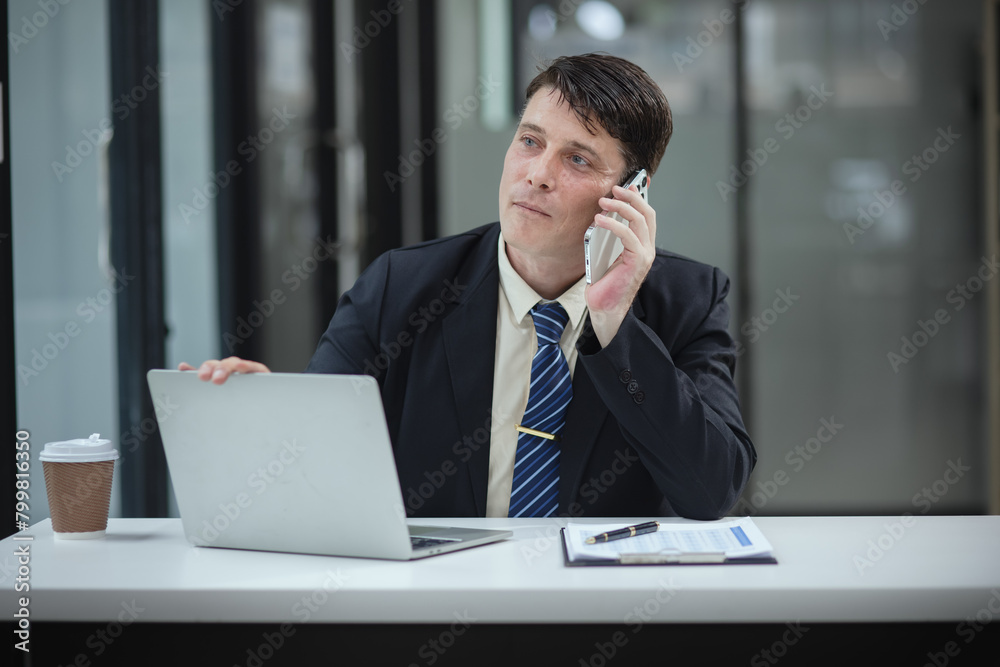 Businessman with smartphone and laptop and analyzing a chart while working in the office, Business and financial concept. Businessman with smartphone and laptop and analyzing a chart while working in the office, Business and financial concept.