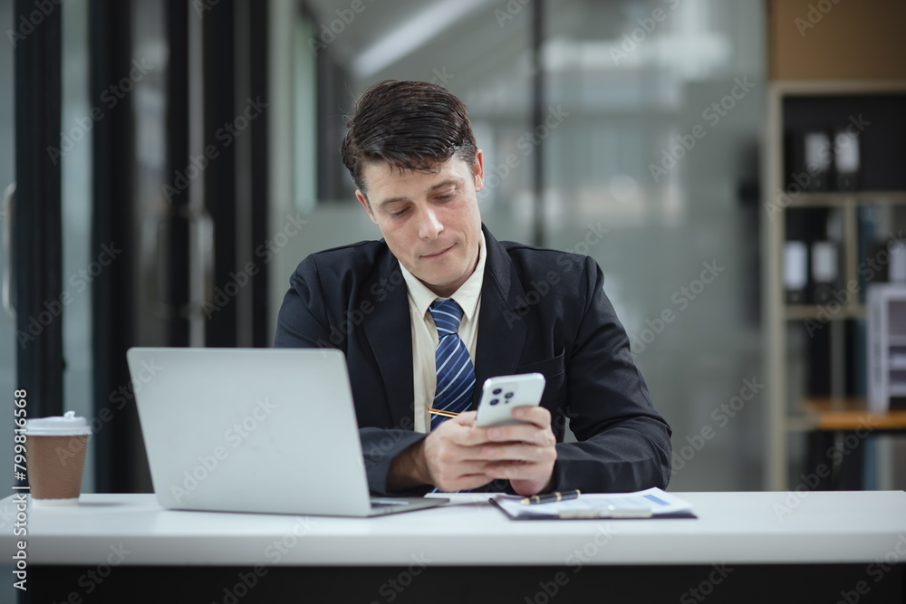 Businessman with smartphone and laptop and analyzing a chart while working in the office, Business and financial concept. Businessman with smartphone and laptop and analyzing a chart while working in the office, Business and financial concept.