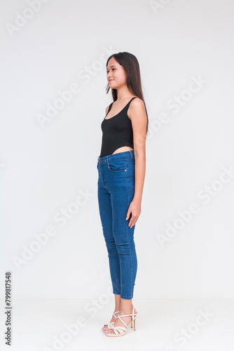 45 degree view of a young asian woman in a black bodysuit and jeans Isolated on a white background. Whole body photo.