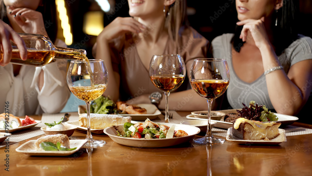 A group of beautiful women talking and having fun together in a restaurant in the evening. A group of girlfriends enjoying food and having fun. Lifestyle concept with happy women on the terrace. A group of beautiful women talking and having fun together in a restaurant in the evening. A group of girlfriends enjoying food and having fun. Lifestyle concept with happy women on the terrace.