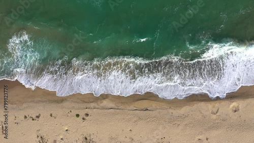 Aerial view of a remote sandy beach and sea waves by drone
