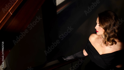 A mysterious and beautiful woman in an evening dress climbs the stairs into a smoky room. Fabulous atmosphere. Close-up