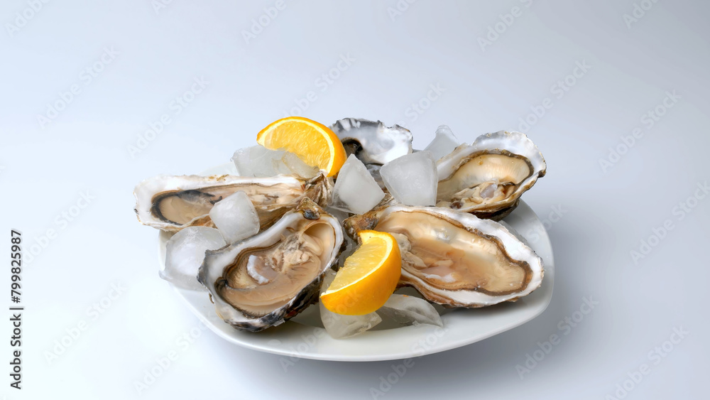 A plate of oysters with lemon on a gray background. Served with oysters and lemon. Fresh oysters close up. Healthy sea food. Oyster dinner in a restaurant. Oysters with lemon. A plate of oysters with lemon on a gray background. Served with oysters and lemon. Fresh oysters close up. Healthy sea food. Oyster dinner in a restaurant. Oysters with lemon.