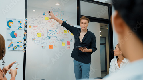 Professional male leader presents start up project by using mind map, colorful sticky notes and business statistic graph with confident while investor listening carefully. Immaculate.