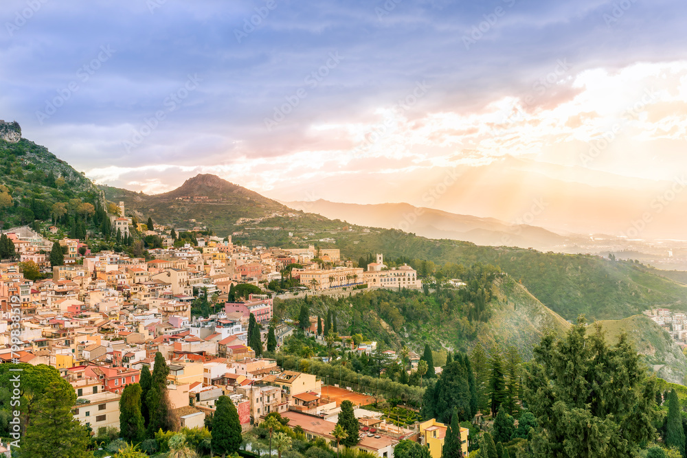 travel landscape of a highland mediterranean town with yellow buildings,  green trees and gardens, beautiful mountains and amazing cloudy sunset