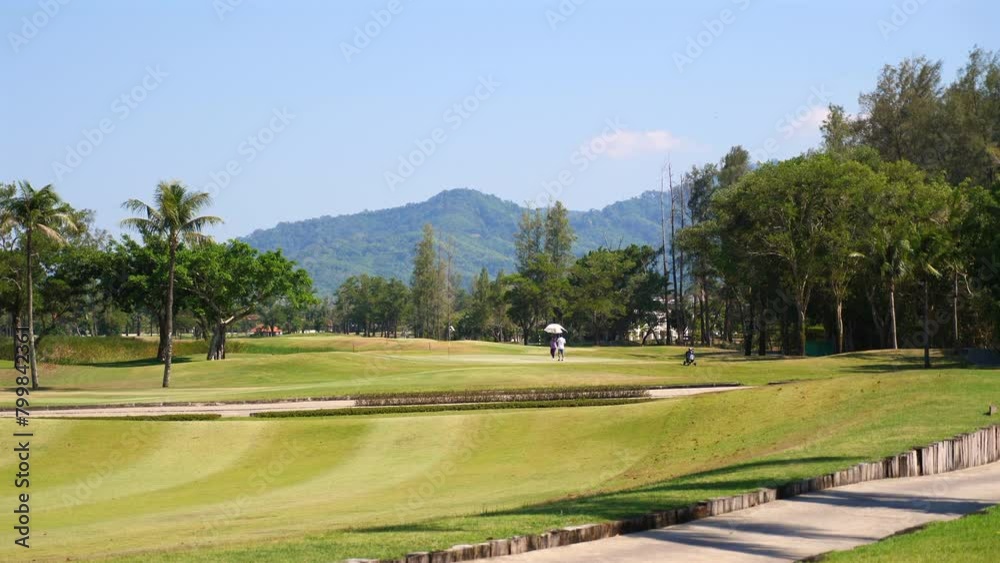 Serene golf course landscape with golfer in distance, tropical mountains and clear blue sky background. Leisure and sports in nature. Serene golf course landscape with golfer in distance, tropical mountains and clear blue sky background. Leisure and sports in nature.
