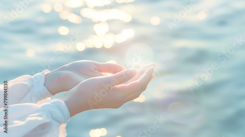 A person's hands are open and facing the camera, with the water in the background. Concept of peace and serenity, as if the person is offering a gesture of love or hope