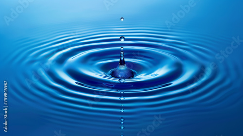 A drop of water is falling into a large blue wave. The water is calm and peaceful, with the drops creating a ripple effect in the water. Concept of tranquility and serenity