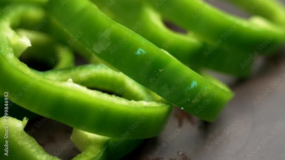 Slices of sweet bell green pepper closeup on a rustic wooden surface. Rotation Slices of sweet bell green pepper closeup on a rustic wooden surface. Rotation