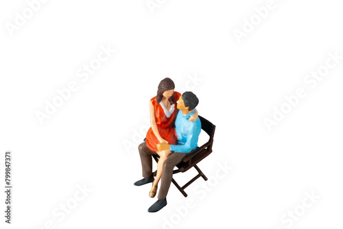 Miniature people , young man and woman sit together on chair Isolated on white background with clipping path