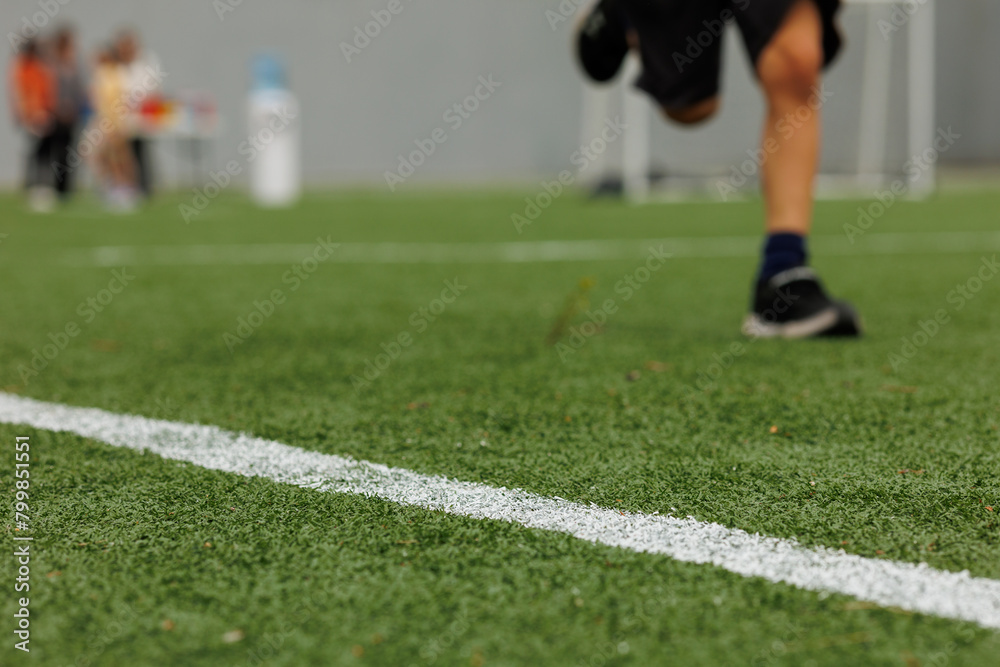 Green synthetic grass sports field with white diagonal line from above. Sports background for product display banner Green synthetic grass sports field with white diagonal line from above. Sports background for product display banner