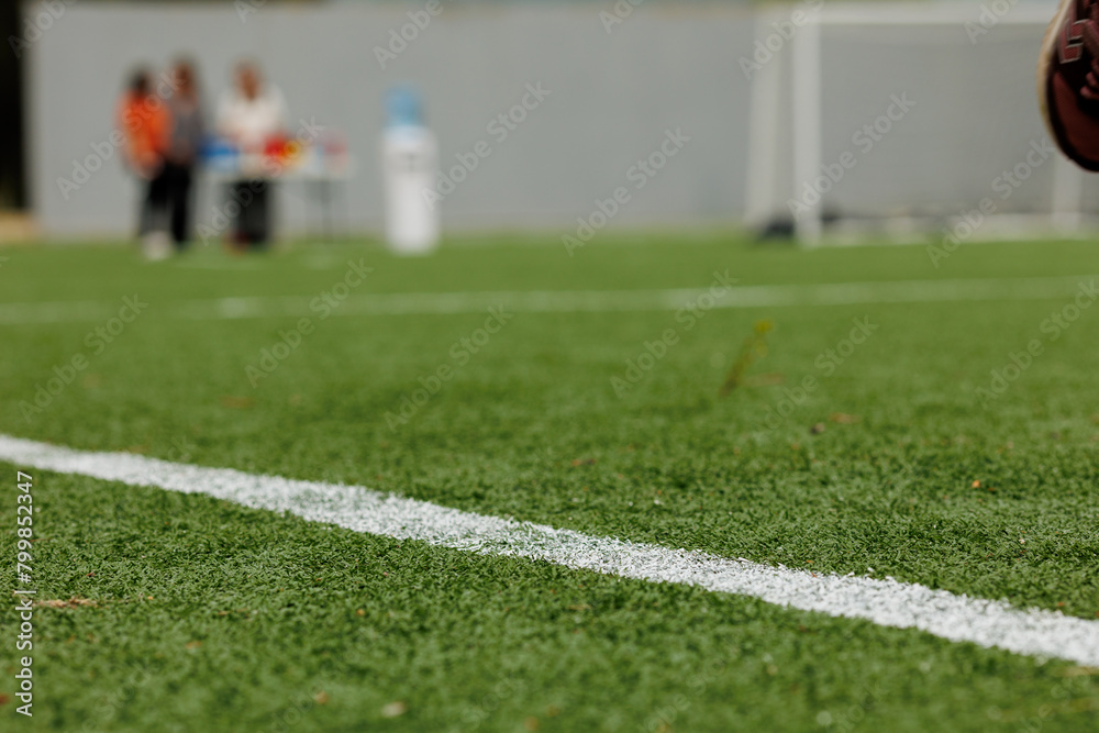 Green synthetic grass sports field with white diagonal line from above. Sports background for product display banner Green synthetic grass sports field with white diagonal line from above. Sports background for product display banner