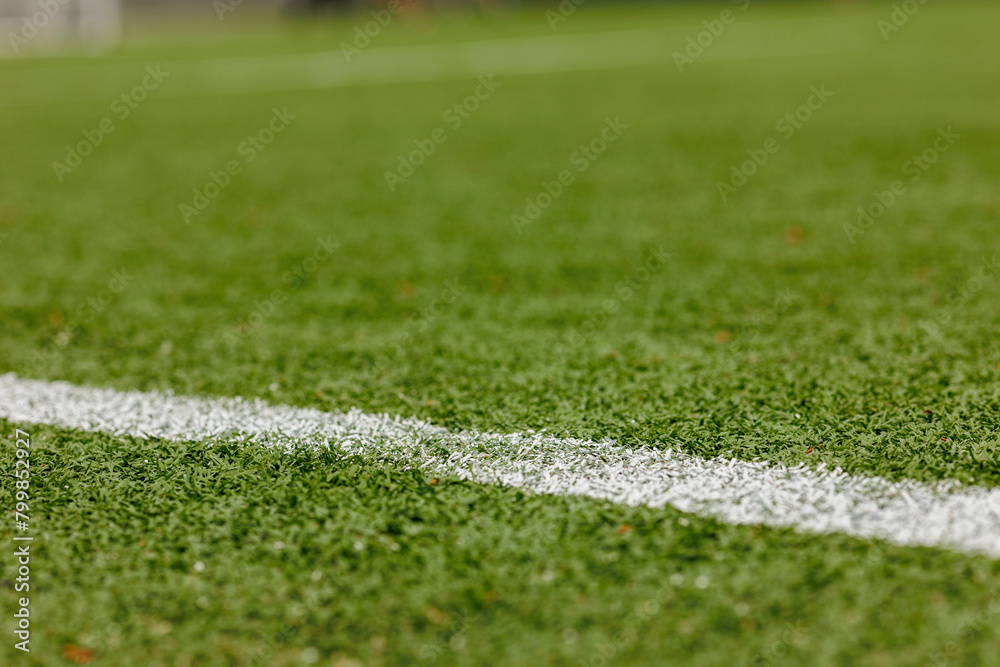 Green synthetic grass sports field with white diagonal line from above. Sports background for product display banner 