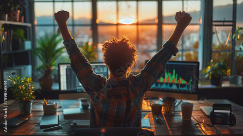 Back view of a person celebrating success in front of a laptop with stock market graphs