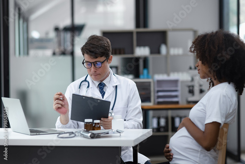 Male doctor examining a pregnant African American woman at the hospital.